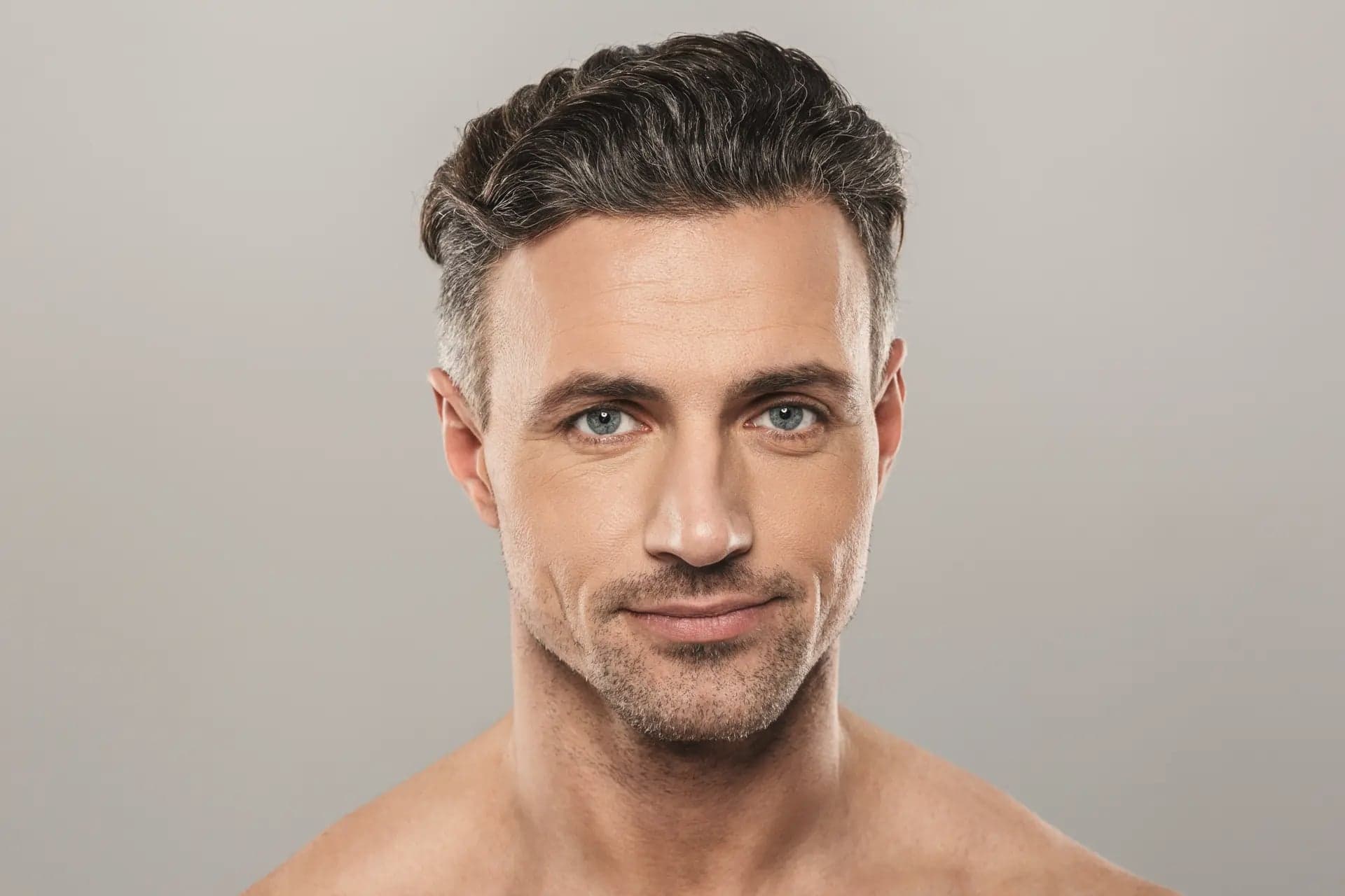 Close-up portrait of a bare-shouldered man with salt-and-pepper hair