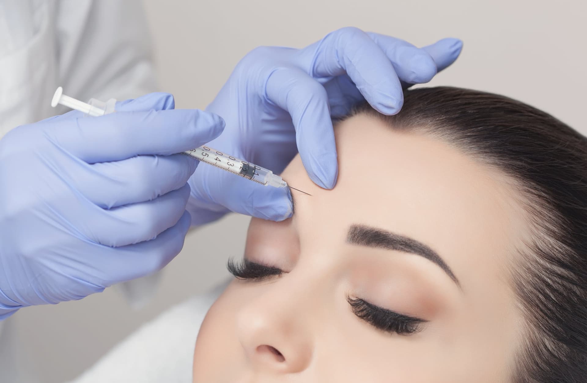 Provider injecting a woman's forehead with a cosmetic neuromodulator