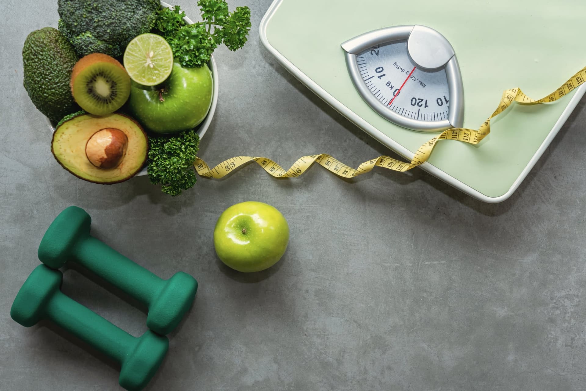 Healthy diet flatlay with fruit, vegetables, dumbbells, and a bathroom scale