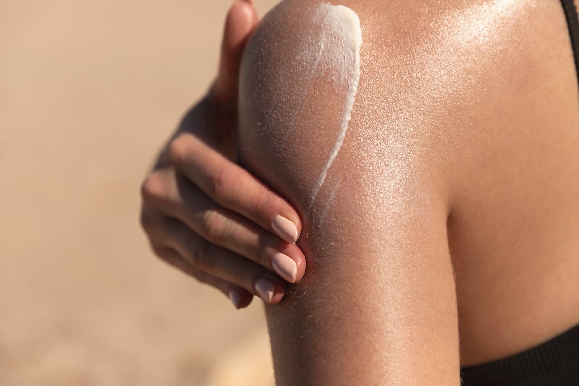Close-up of a woman applying sunscreen to her sun-kissed shoulder