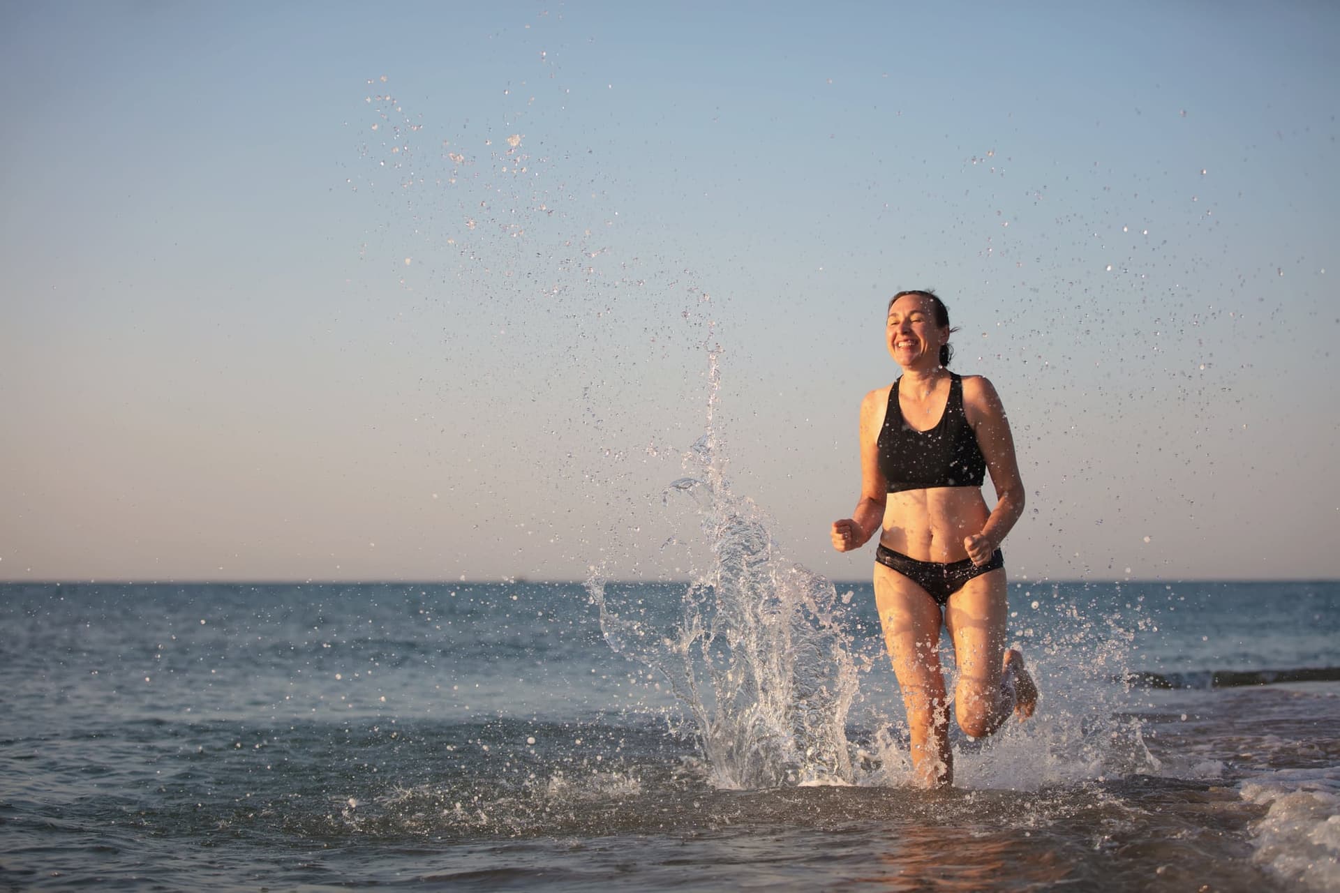Woman joyfully running through ocean waves at the beach
