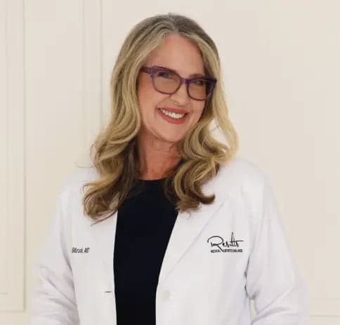 Smiling physician wearing glasses and a white lab coat, studio portrait