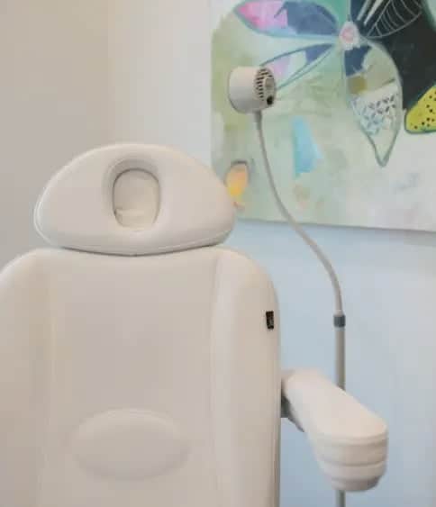 Treatment room chair beside a wall-mounted magnifying lamp
