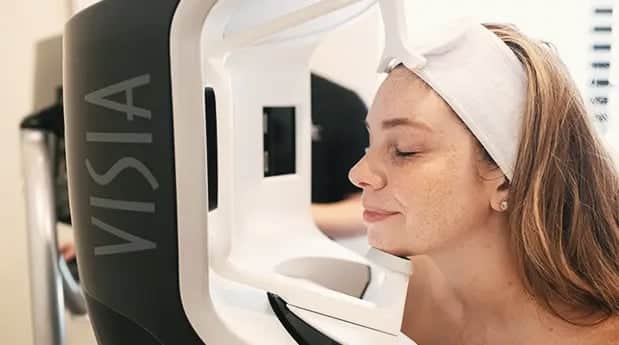 Client undergoing a VISIA facial skin analysis scan at the clinic