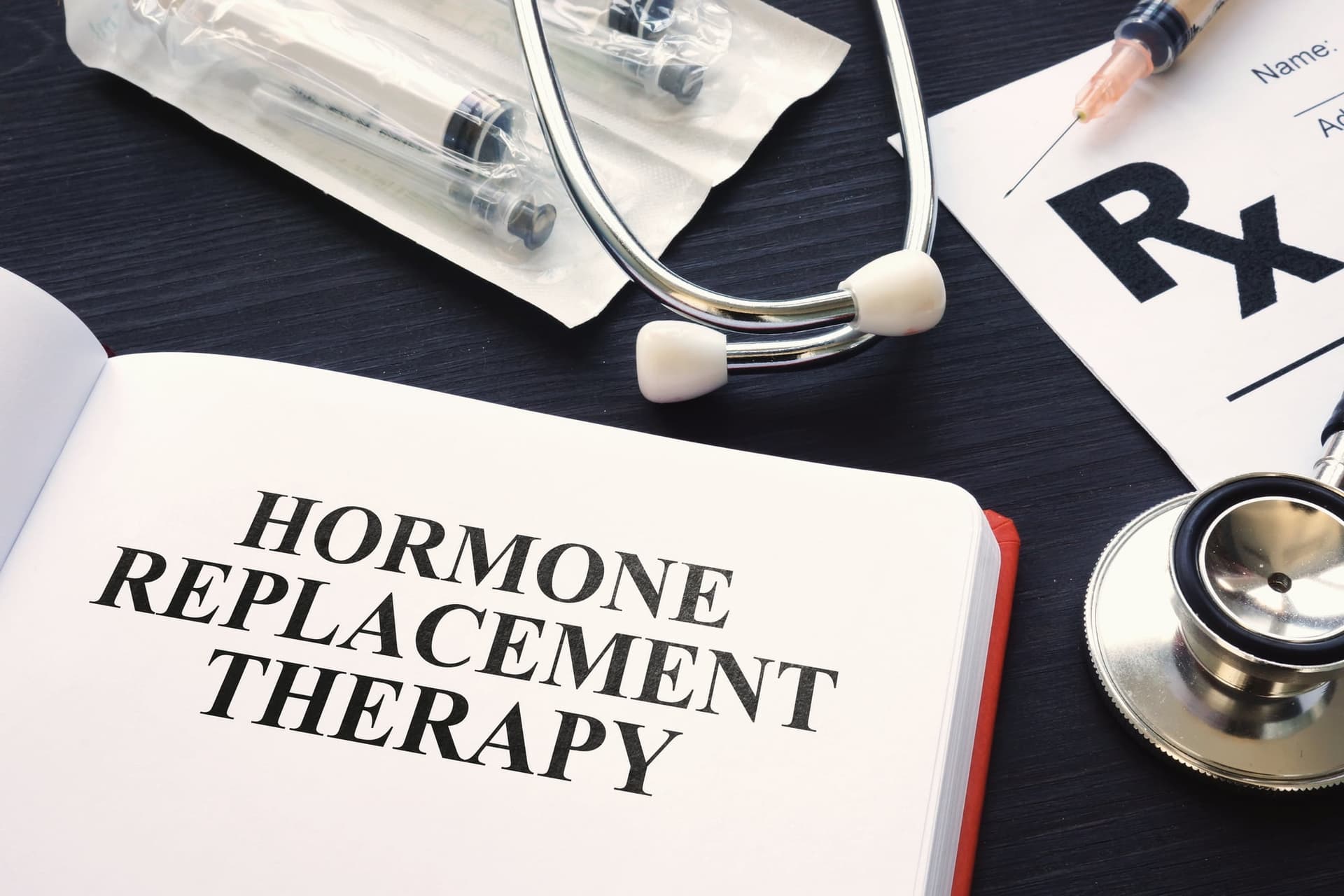 Hormone Replacement Therapy book beside a stethoscope and prescription pad