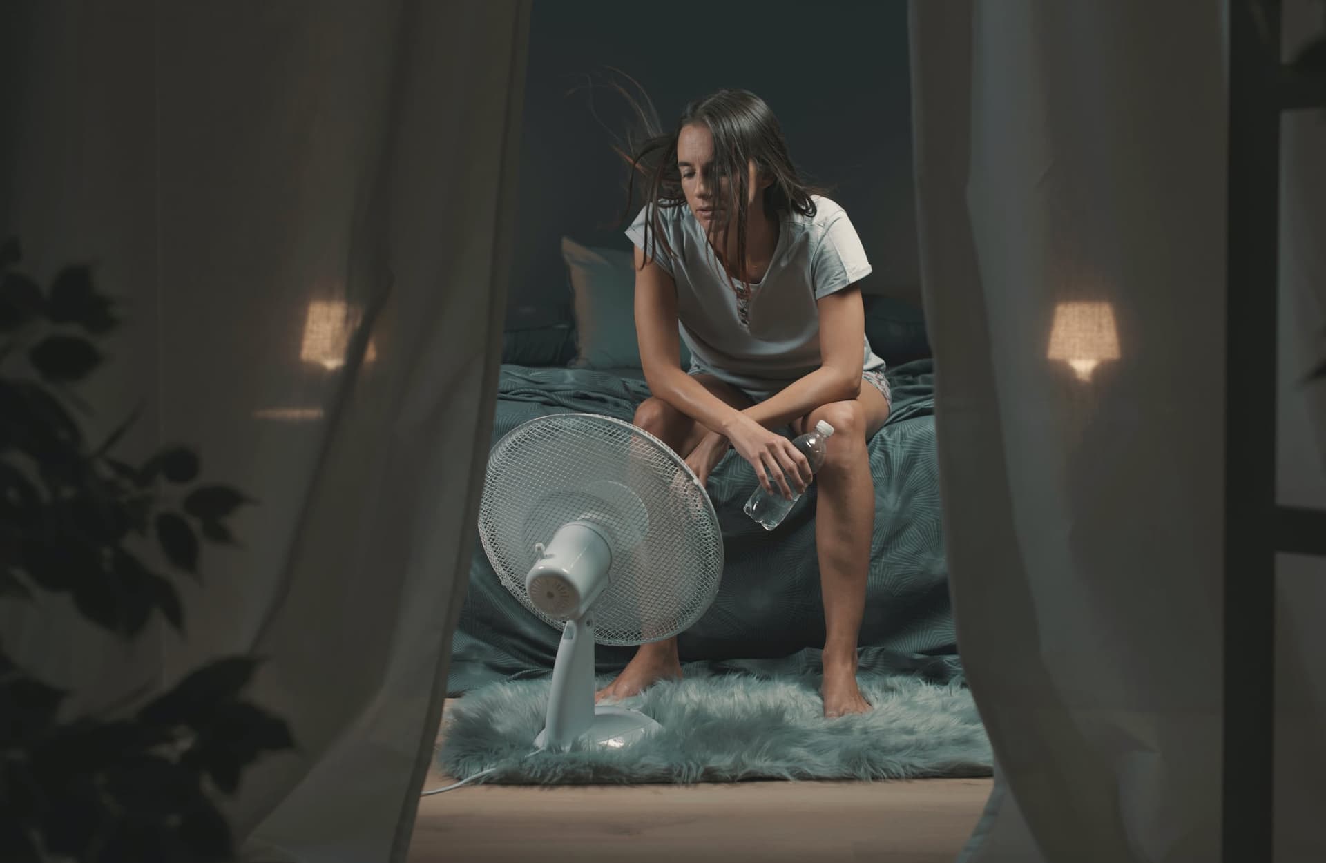 Woman cooling off with a fan during a nighttime hot flash