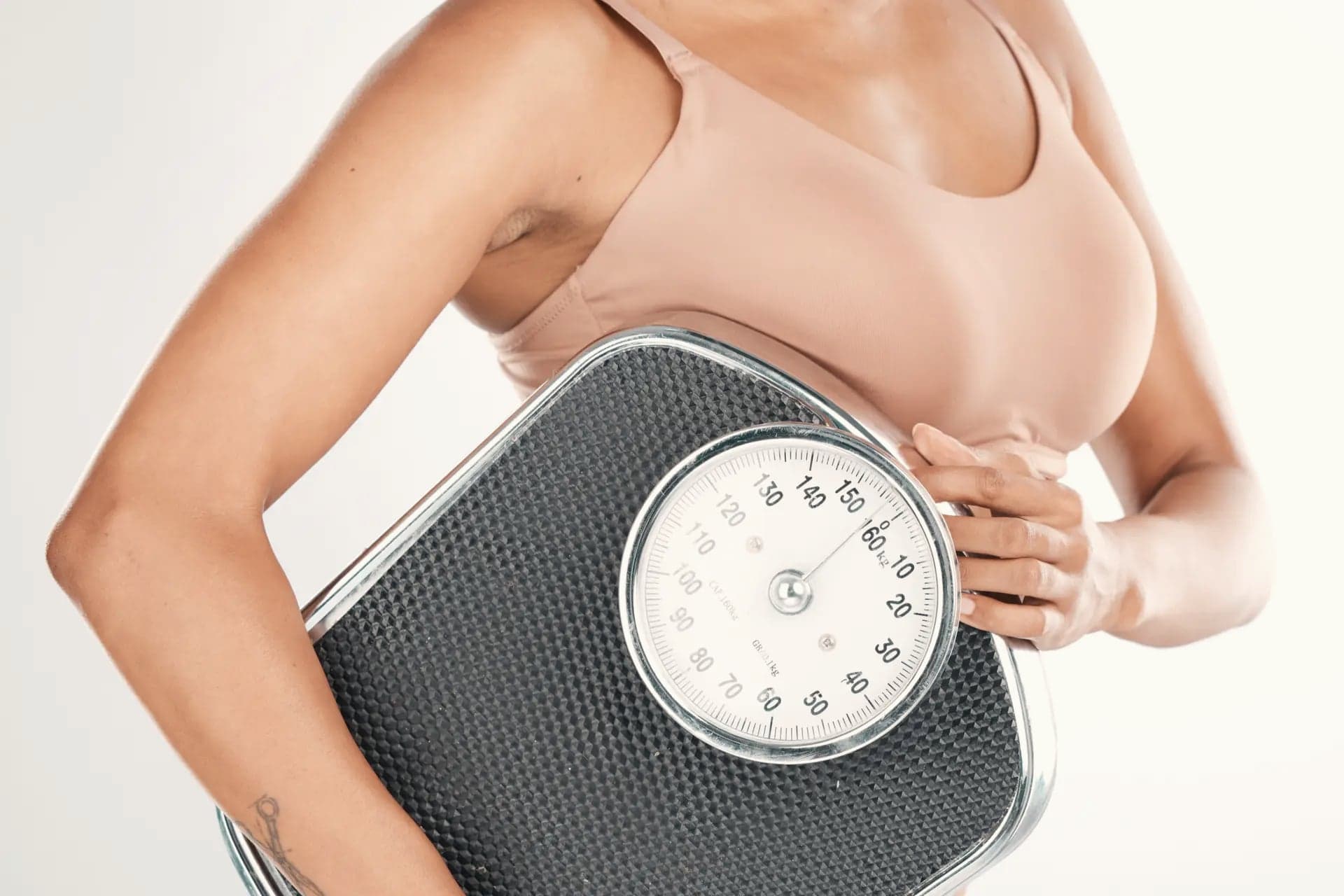 Woman's midsection holding a bathroom scale against her chest