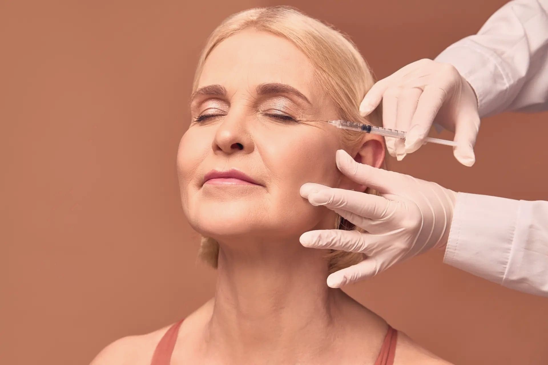 Provider injecting a relaxed woman's forehead with a syringe